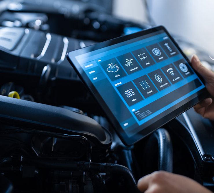 A mechanic using a tablet to perform a digital inspection on a car